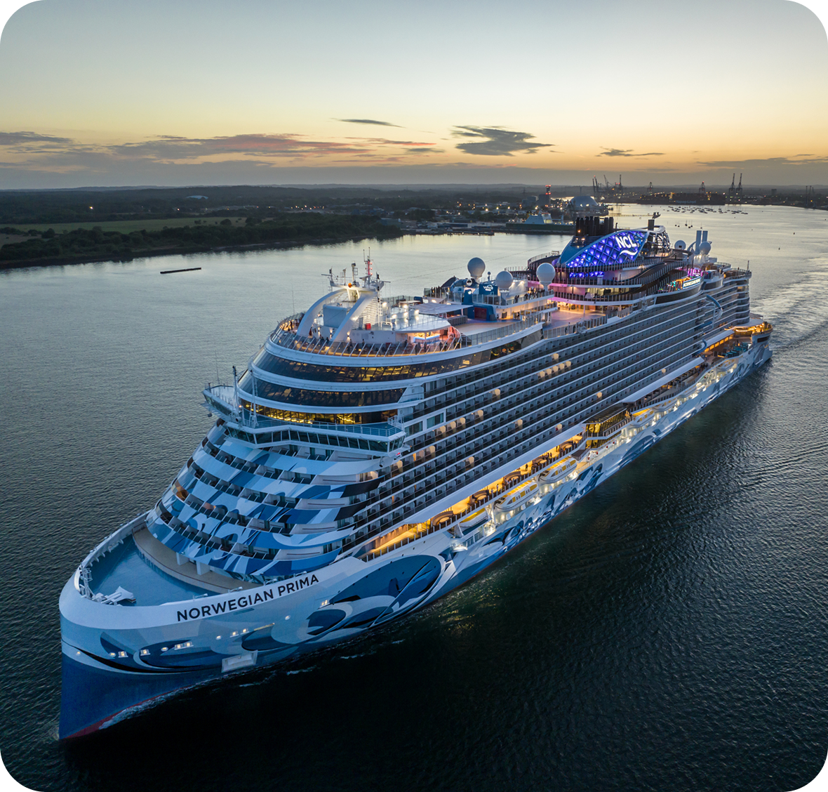 Cruise ship sailing at sunset, illuminated lights.